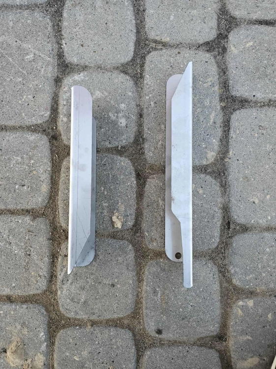 Prawa łopatka talerza rozsiewacza Tytan - komplet dwóch metalowych elementów pokazany na utwardzonym podłożu.